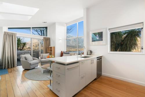 uma cozinha com armários brancos e uma sala de estar com janelas em A Stunning Stay - Queenstown Holiday Home em Queenstown