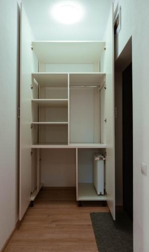 a walk in closet with white shelves and a door at Solomon Apartments ap 1 in Sângeorgiu de Mureș