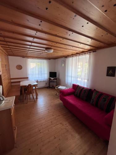 una sala de estar con sofá rojo y techos de madera. en Apartments Roemerschlucht en Velden am Wörthersee