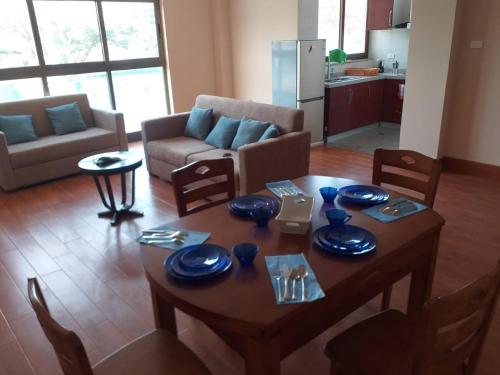 a living room with a wooden table and a kitchen at Queen M Palace in Addis Ababa