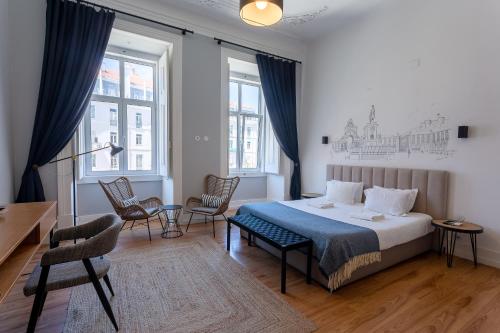 a bedroom with a bed and chairs and windows at Lisbon Check-In Guesthouse in Lisbon