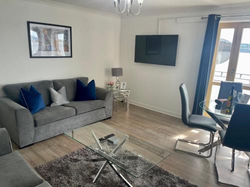 uma sala de estar com um sofá e uma mesa de vidro em Casa Fresa - City Quay Apartment em Dundee