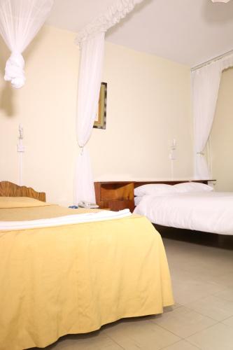 two beds in a hotel room with white walls at Adventist LMS Guest House & Conference Centre in Nairobi