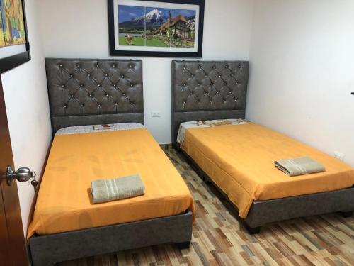 two beds in a small room with orange sheets at Piso 3-Apartment near to Cali airport in Palmira