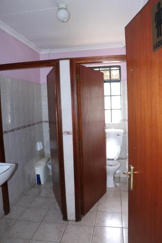 a bathroom with a toilet and a sink and a door at Adventist LMS Guest House & Conference Centre in Nairobi