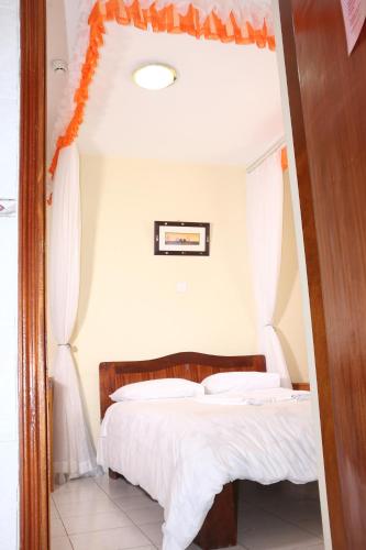 a bedroom with a bed with white sheets and an orange canopy at Adventist LMS Guest House & Conference Centre in Nairobi
