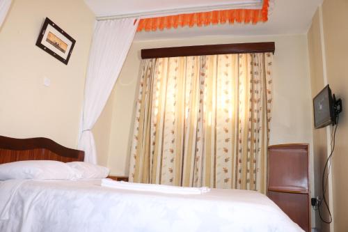 a bedroom with a bed and a window with curtains at Adventist LMS Guest House & Conference Centre in Nairobi
