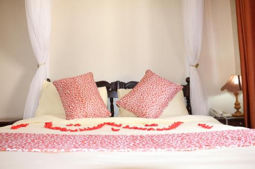 a bed with red and white pillows on it at Adventist LMS Guest House & Conference Centre in Nairobi