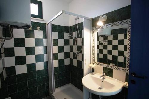 baño verde y blanco con lavabo y ducha en SERENA SWEET HOUSE, en SantʼAndrea Apostolo dello Ionio