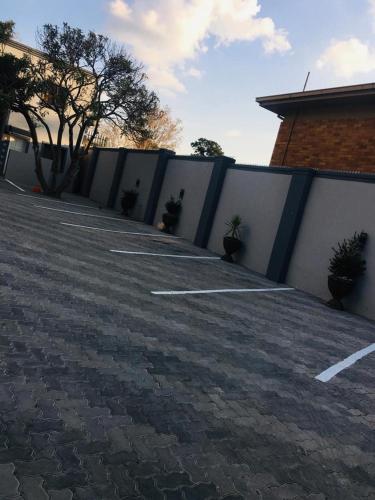 a parking lot with a fence and some plants at Classy Guest House in Johannesburg