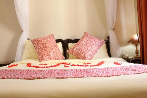 a bed with pink and white pillows on it at Adventist LMS Guest House & Conference Centre in Nairobi