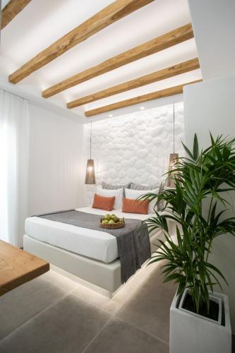 a white bedroom with a bed and a potted plant at Kamvas Deluxe Apartments in Naxos Chora