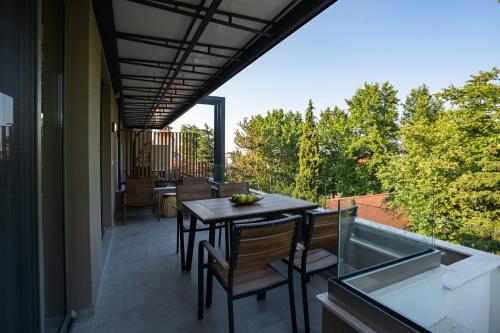 eine Terrasse mit einem Tisch und Stühlen auf dem Balkon in der Unterkunft Funtuki Seaside Apartments in Leptokaryá