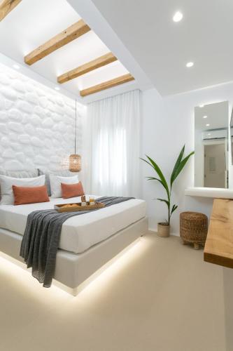 a white bedroom with a bed and a plant at Kamvas Deluxe Apartments in Naxos Chora