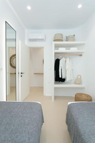 a white room with two beds and a closet at Kamvas Deluxe Apartments in Naxos Chora