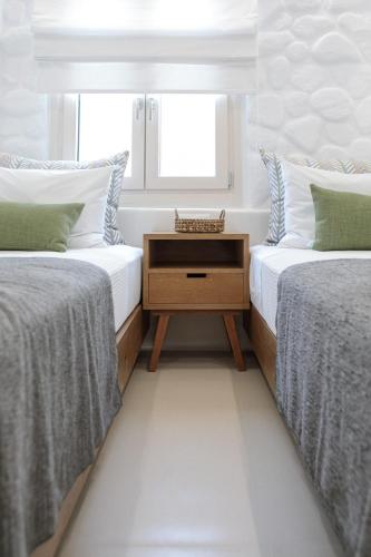two beds in a room with a table between them at Kamvas Deluxe Apartments in Naxos Chora
