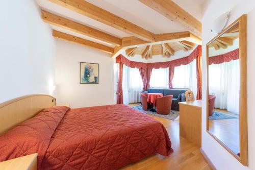 a bedroom with a bed with a red bedspread at Flos Hotel in Moena