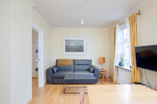 un salon avec un canapé bleu et une télévision dans l'établissement Live as Locals Apartments, à Reykjavik