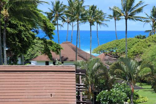 une maison avec des palmiers et l'océan en arrière-plan dans l'établissement Kiahuna Plantation 96, Poipu Beach, Athletic Club Membership, Part Ocean View, à Koloa