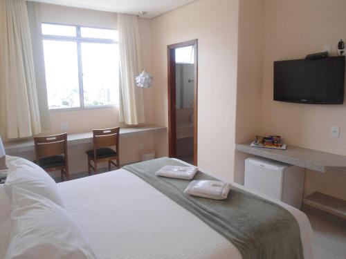 a hotel room with a bed and a television at Pousada Sossego da Pampulha in Belo Horizonte