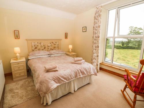 a bedroom with a bed and a window and a chair at Dinas Farmhouse Annex in Caernarfon