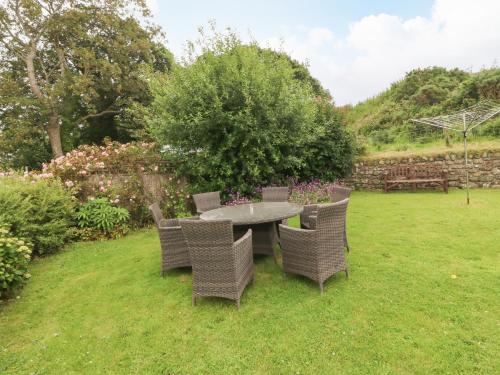 a table and chairs in a yard with flowers at Dinas Farmhouse Annex in Caernarfon