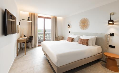 sypialnia z dużym białym łóżkiem i biurkiem w obiekcie Le Mirage w mieście Bormes-les-Mimosas