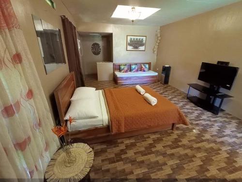 een slaapkamer met een bed en een flatscreen-tv bij Casa de Cortijo in Pagbilao