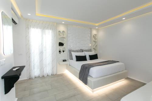 a white bedroom with a bed and a window at Kamvas Deluxe Apartments in Naxos Chora