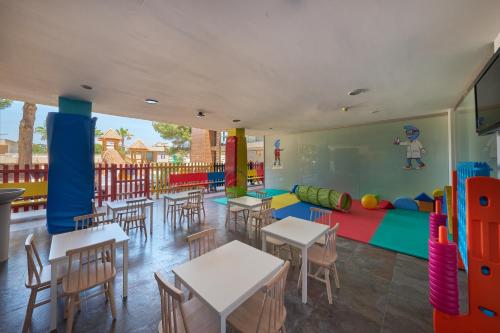 a classroom with tables and chairs and a play area at Occidental Cala Viñas in Cala Vinyes