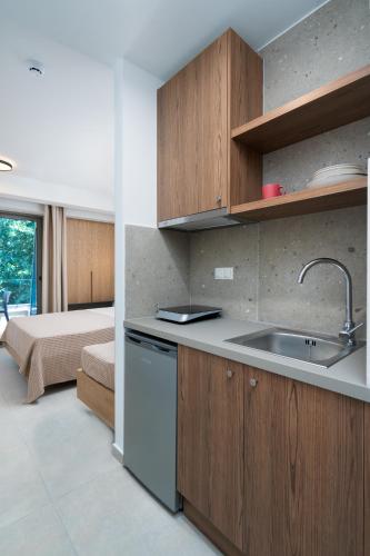 a kitchen with wooden cabinets and a sink and a bed at Funtuki Seaside Apartments in Leptokarya