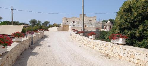 a stone wall with potted plants and a building at Villa Clara in Alberobello