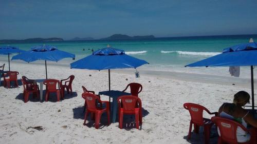 a group of chairs and blue umbrellas on a beach at ECONOMICS- AMPLO, VENTILADO E ACONCHEGANTE in Cabo Frio