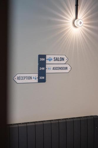 two street signs on a wall with the sun at Kyriad Hotel Laval in Laval
