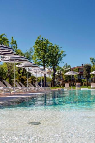 a pool of water with chairs and umbrellas at Hotel Premiere Abano in Abano Terme