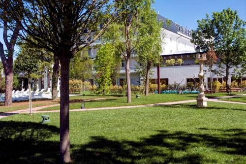 a building in a park with a tree in the foreground at Hotel Premiere Abano in Abano Terme