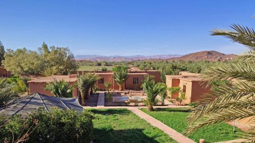 a home in the middle of a desert with palm trees at Maison d'hôtes Tigminou - Adults Only in Aït Benhaddou