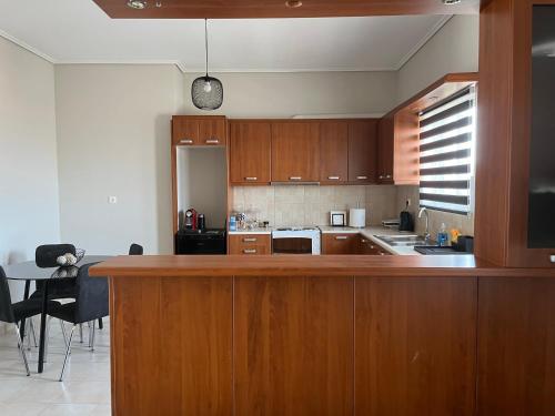 a kitchen with wooden cabinets and a table in it at ILION Air Host - near Athens International Airport in Markopoulo