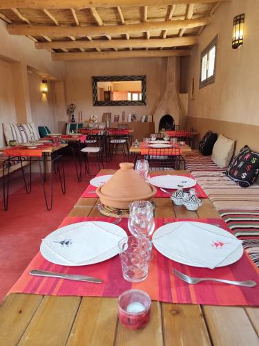 a dining room with a table with plates and glasses at Maison d'hôtes Tigminou - Adults Only in Aït Ben Haddou