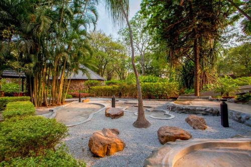a garden with rocks and a tree and trees at StayVista at Ananta - Breakfast Included & Basketball Court in Bengaluru