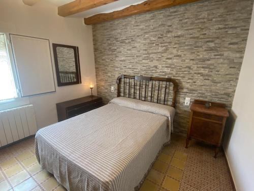 a bedroom with a bed and a brick wall at Cal cap xic in Castellfullit de Riubregós