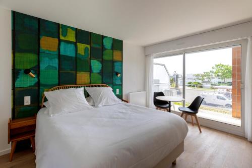 a bedroom with a large white bed and a window at Louison Appart & Suite in Quiberon