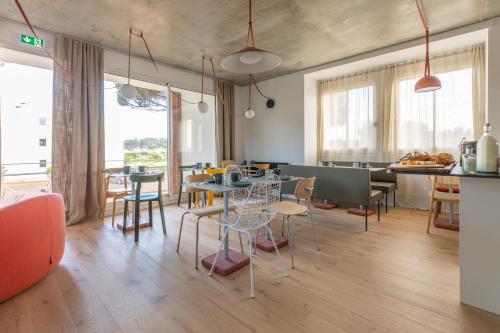 a dining room with tables and chairs and windows at Louison Appart & Suite in Quiberon