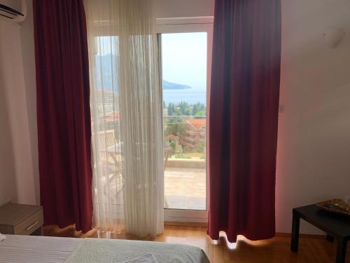 a bedroom with a large window with red curtains at Apartment Dunja in Boreti