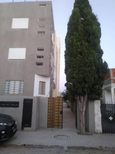 a tree in front of a building with a door at Belle Vue de Mer in Tazarka