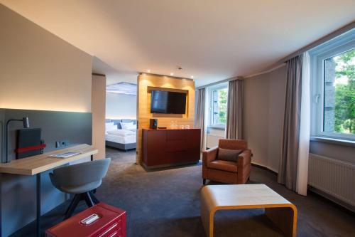 a hotel room with a bed and a desk and chair at ATLANTIC Hotel Airport in Bremen