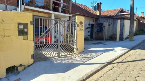 a gate in front of a yellow building at CASA DO BRAZ aptos e casa de temporada in Monte Verde
