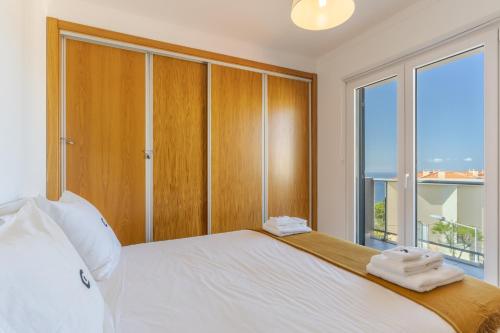een slaapkamer met een bed en een groot raam bij Jardins do Oceano in Caniço