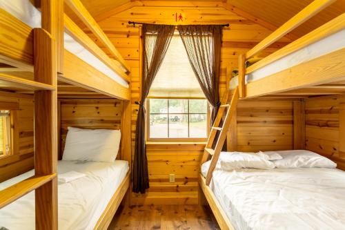 two bunk beds in a wooden room with a window at Drummer Boy Camping Resort in Gettysburg