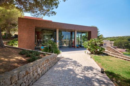 a brick building with a walkway in front of it at Occidental Cala Viñas in Cala Vinyes